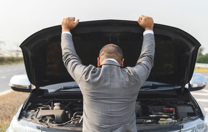 An open car hood reveals a dirty engine compartment with caked-on grime, possibly indicating a lack of proper maintenance during a car lease.