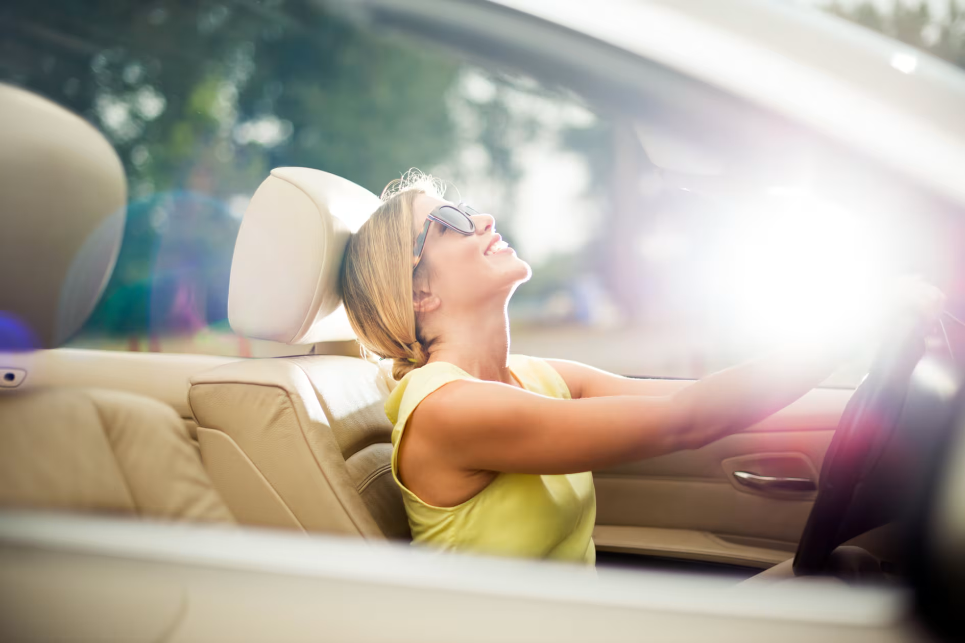 A woman enjoys a sunny day in her newly bought car.