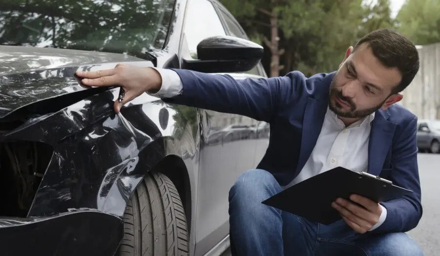 An insurance agent inspects a scratched bumper on a leased car, highlighting potential wear and tear charges.